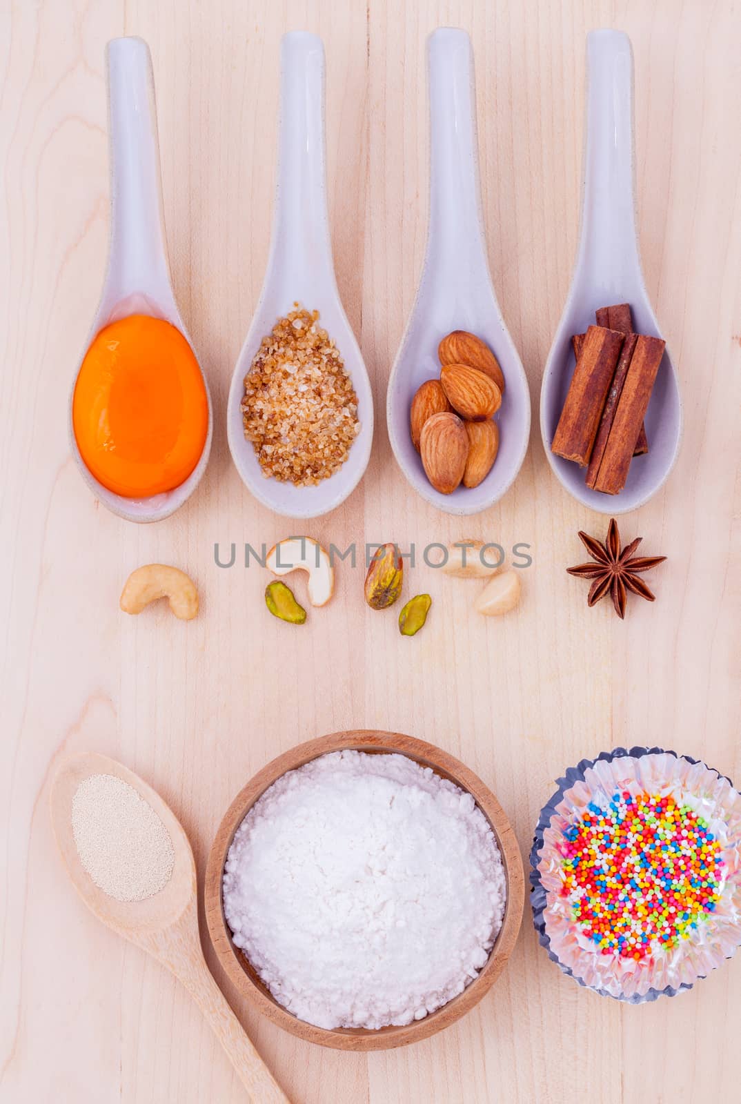 The ingredients of cup cake and the shape of cup cake with topping on wooden table .