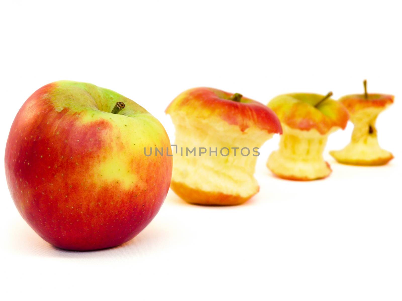 Apples and apple cores lying in a row isolated on white background