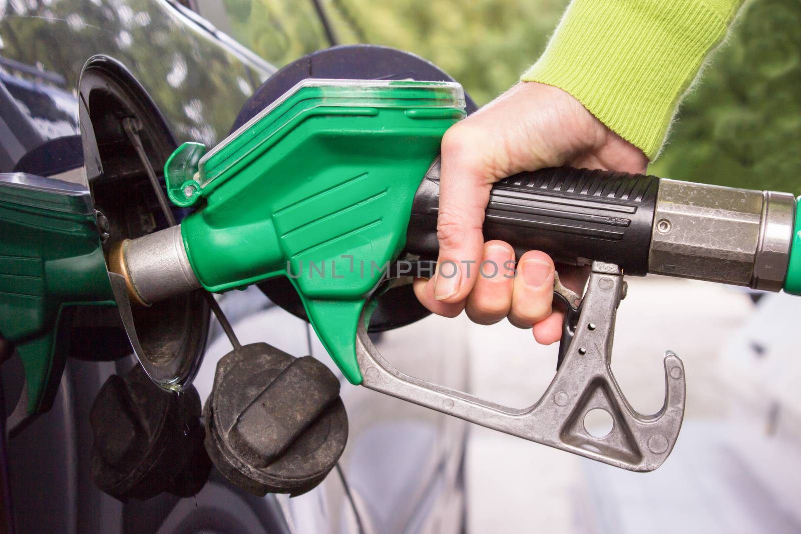 Female hand filling car tank with gasoline by BenSchonewille