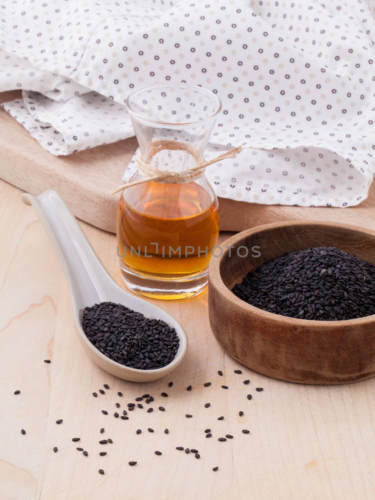 Black sesame oil and sesame seeds set up on wooden table