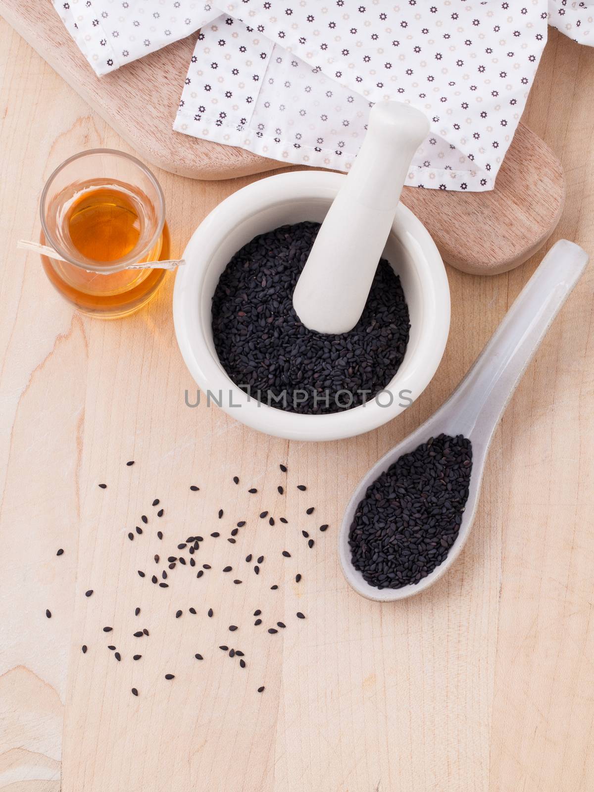 Black sesame oil and sesame seeds set up on wooden table by kerdkanno