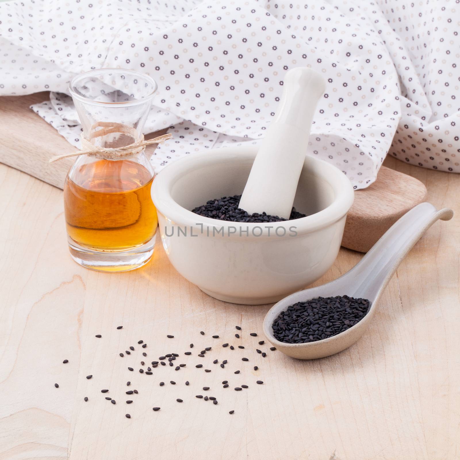 Black sesame oil and sesame seeds set up on wooden table