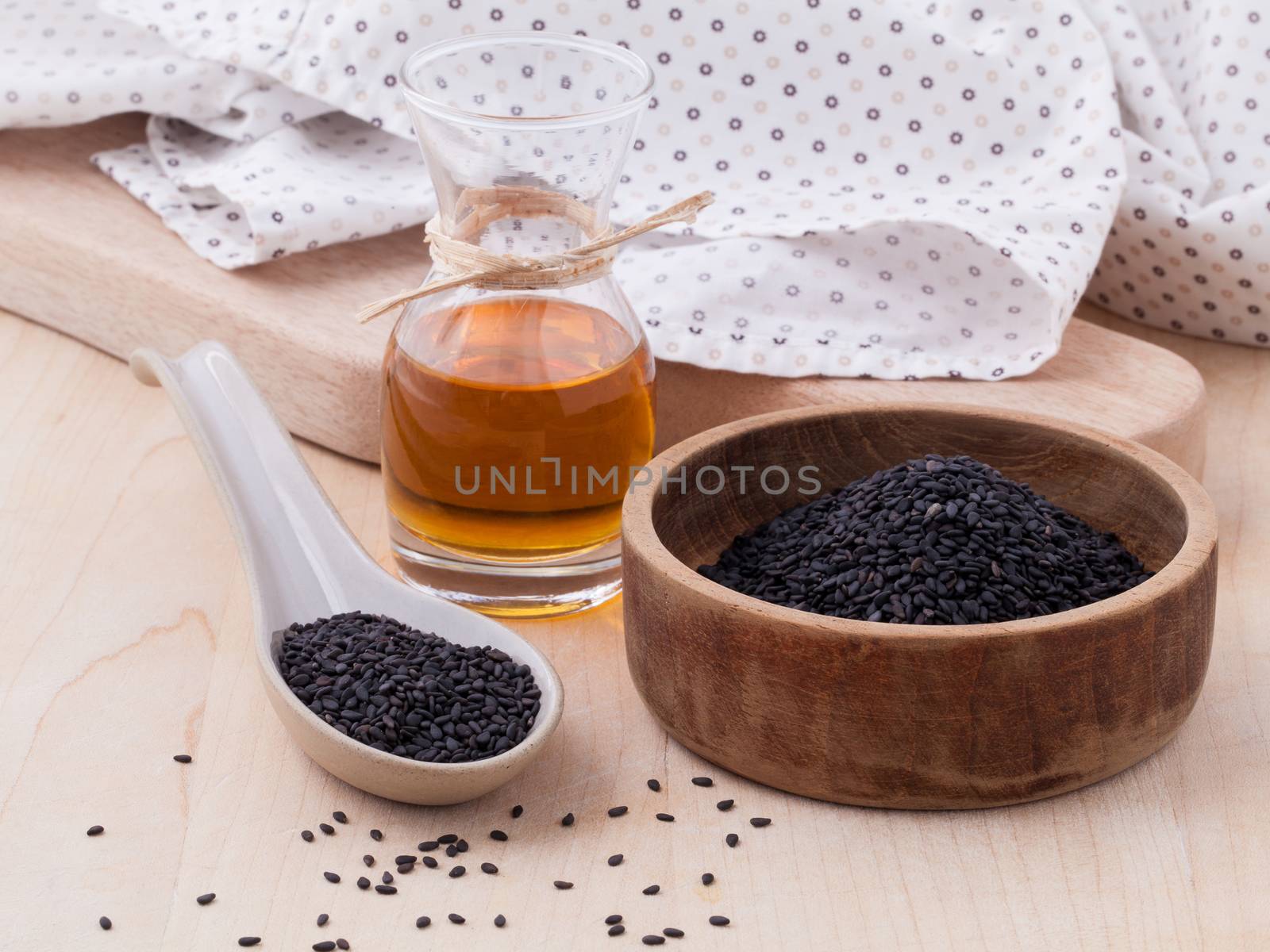 Black sesame oil and sesame seeds set up on wooden table by kerdkanno