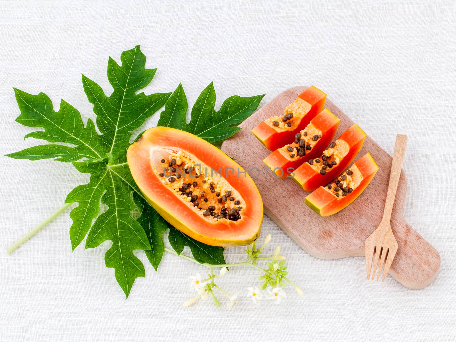 Fresh papaya and papaya slice with papaya leaf on cutting board. by kerdkanno