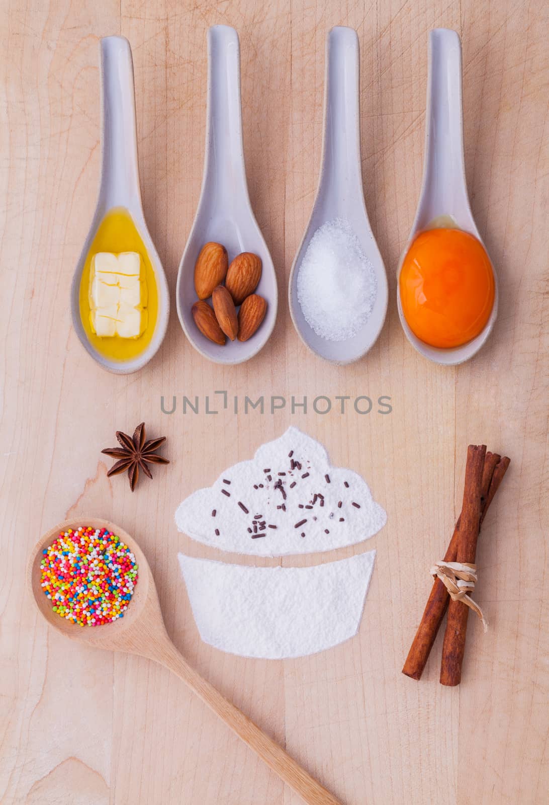 The ingredients of cup cake and the shape of cup cake with topping on wooden table .