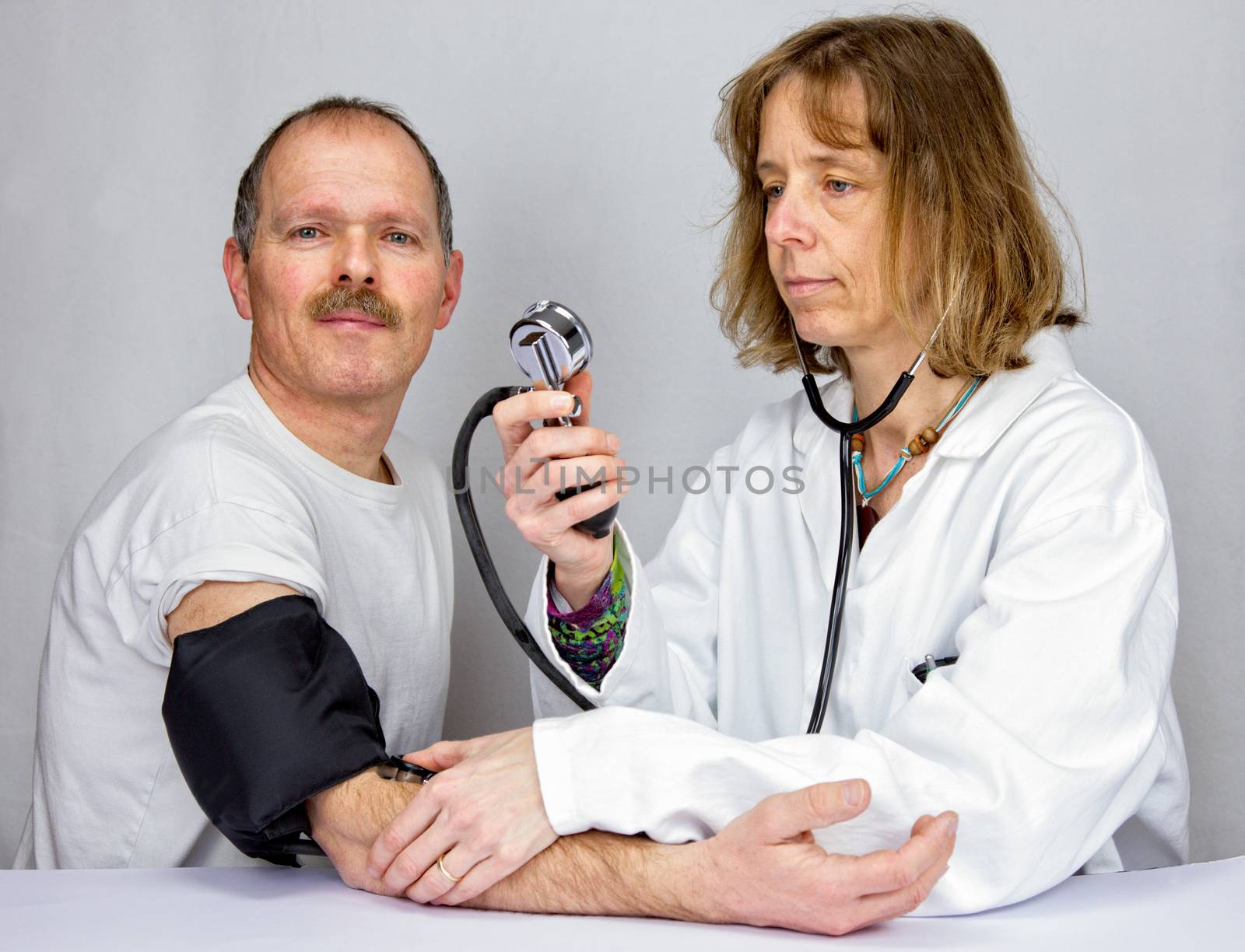 Doctor checks blood pressure of a patient by BenSchonewille
