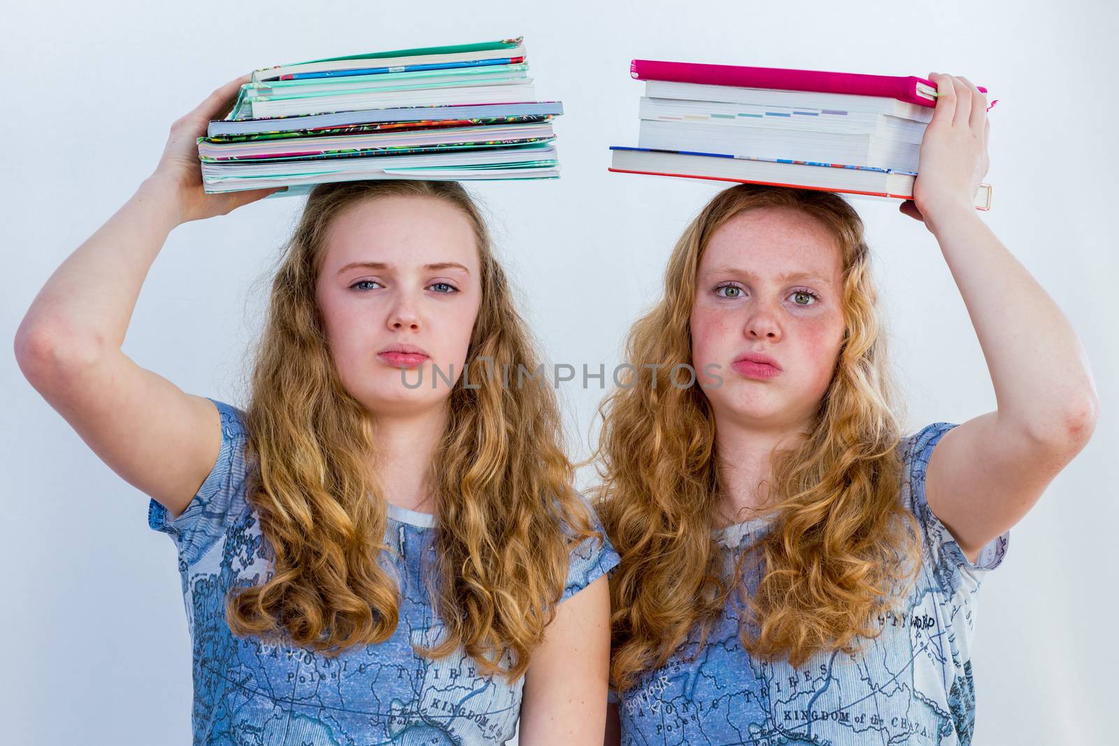 Two european sisters as schoolgirls with books on their head and a bored facial expression