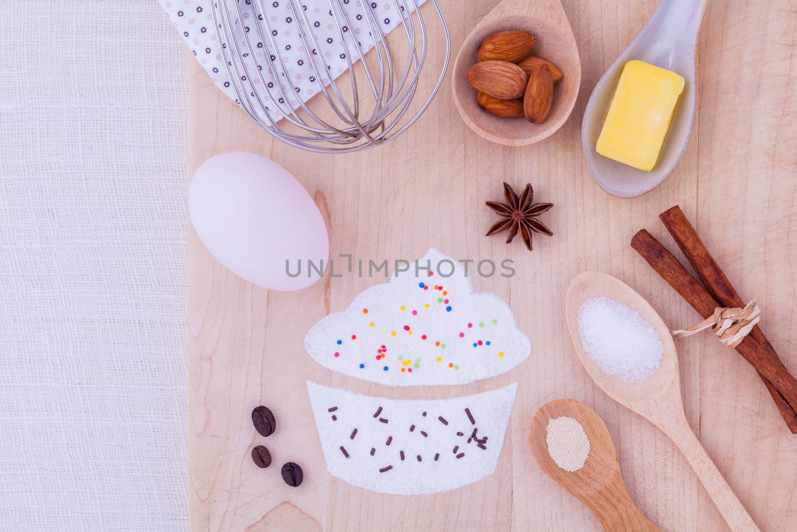 The ingredients of cup cake and the shape of cup cake with topping on wooden table .