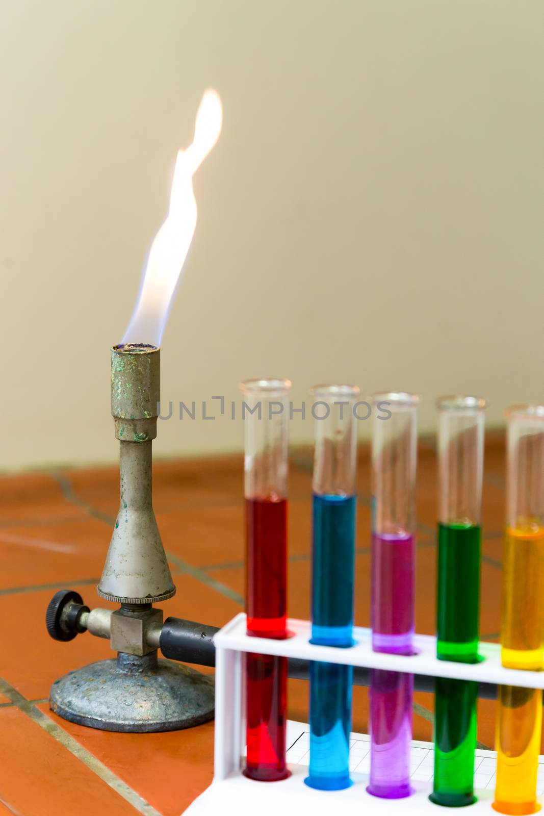 Flaming gas burner with colored test tubes in chemistry lab