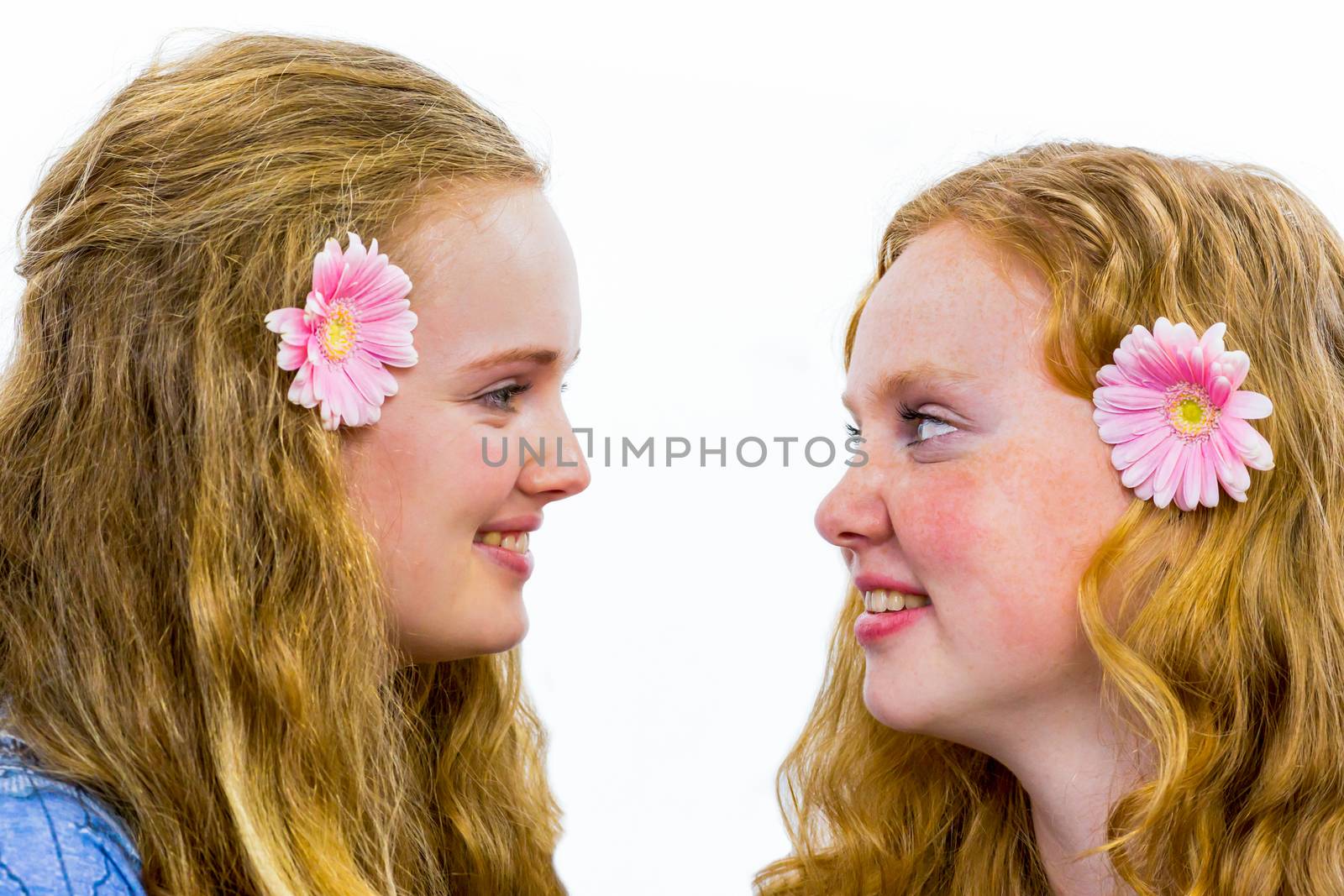 Two caucasian sisters looking and smiling at each other having fun isolated on white background