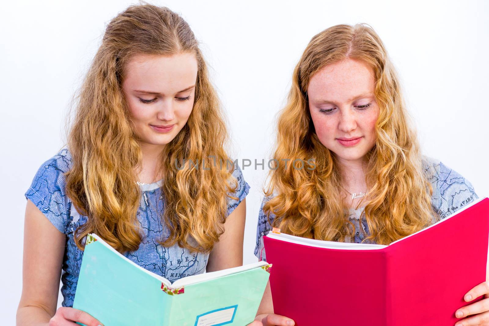 Two caucasian teenage schoolgirls reading books isolated on white background