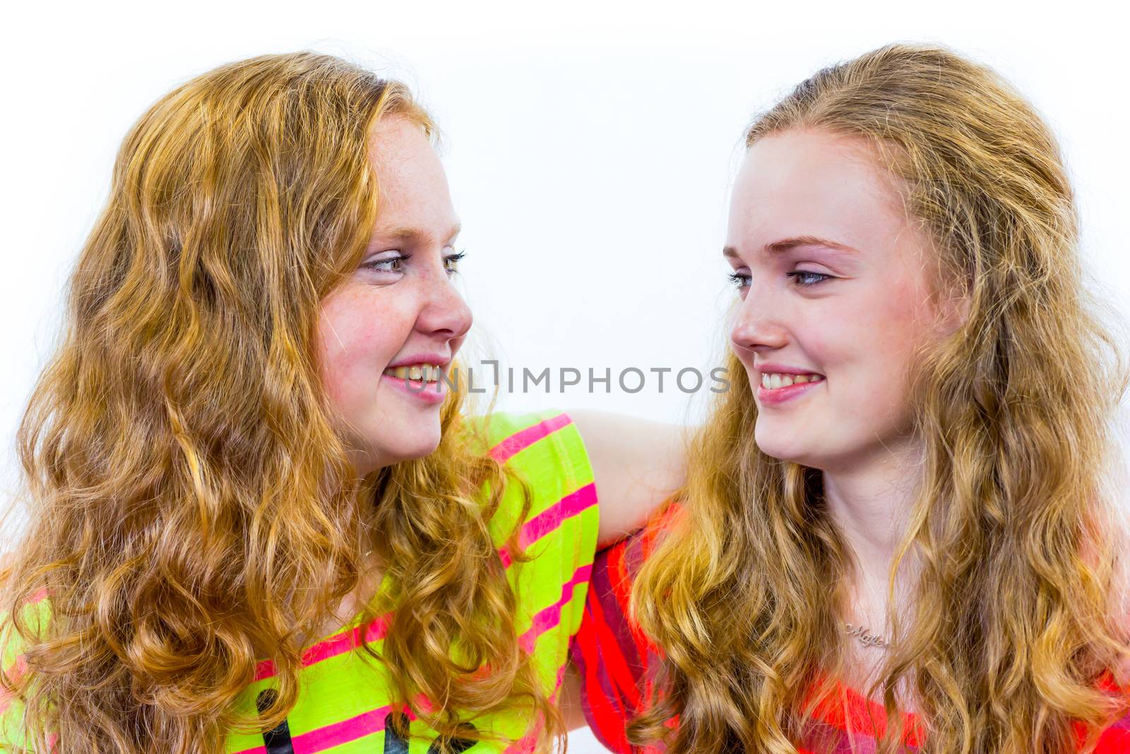 Two caucasian teenage girls embracing each other and laughing having fun  isolated on white background