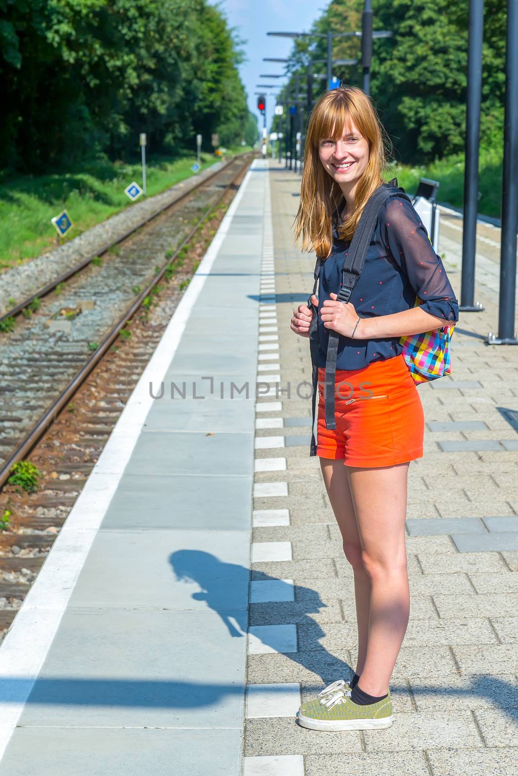Caucasian redhead teenage girl standing at station waiting on train