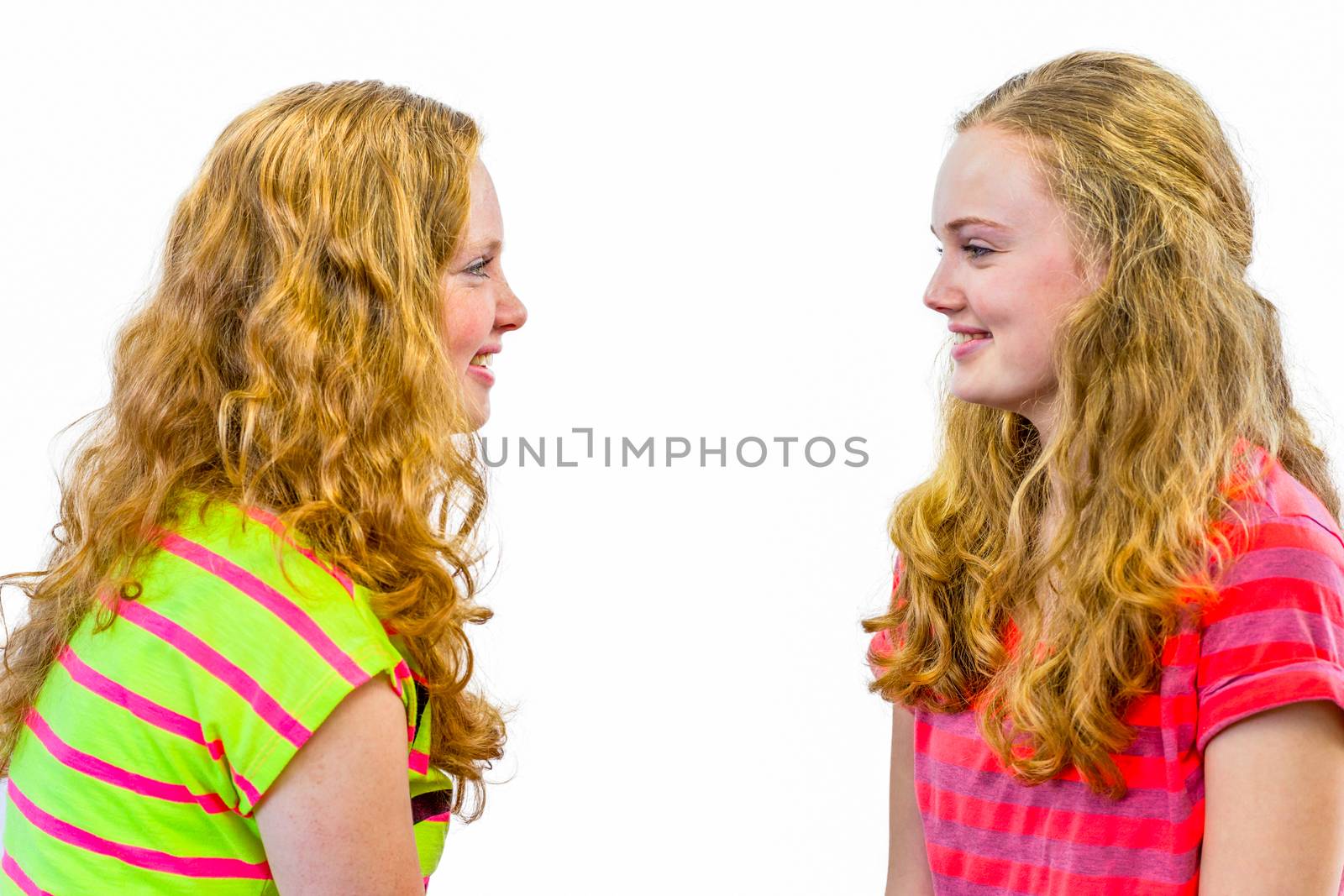 Two caucasian teenage girls smiling and looking at each other