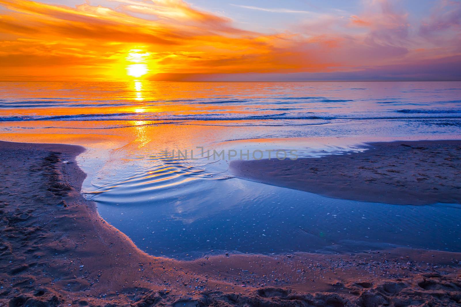 Orange sunset at coast with sea and beach