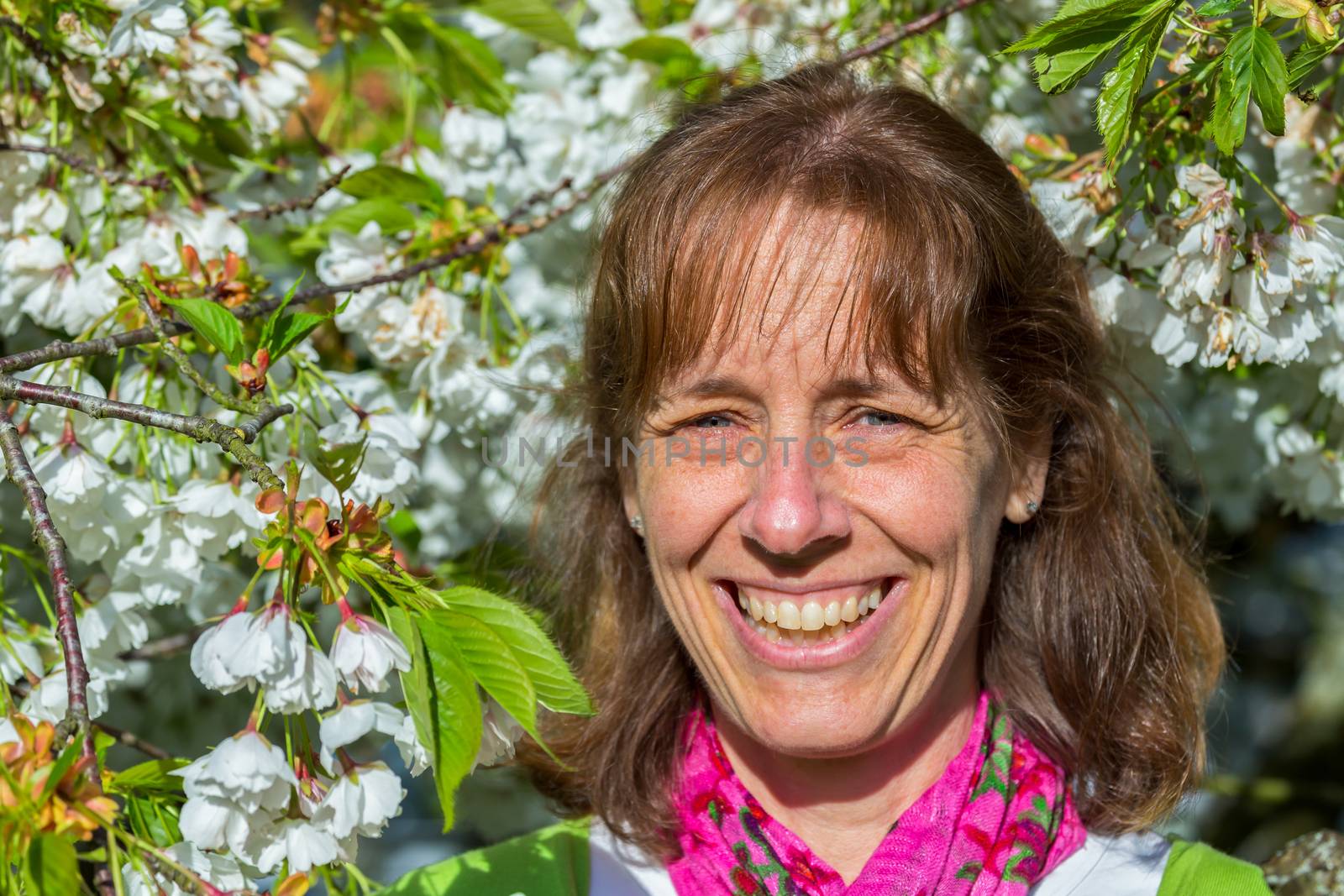 Head of caucasian middle aged woman between white flowers in spring