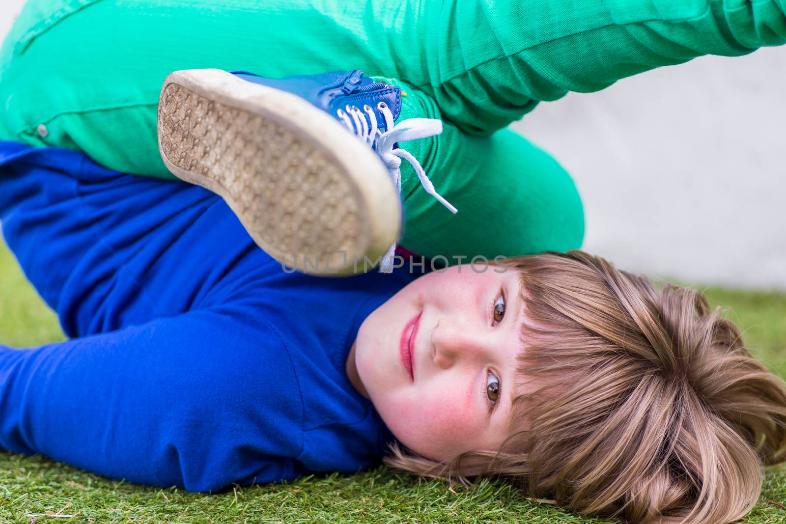 Bent european girl lying on her back on grass at playground