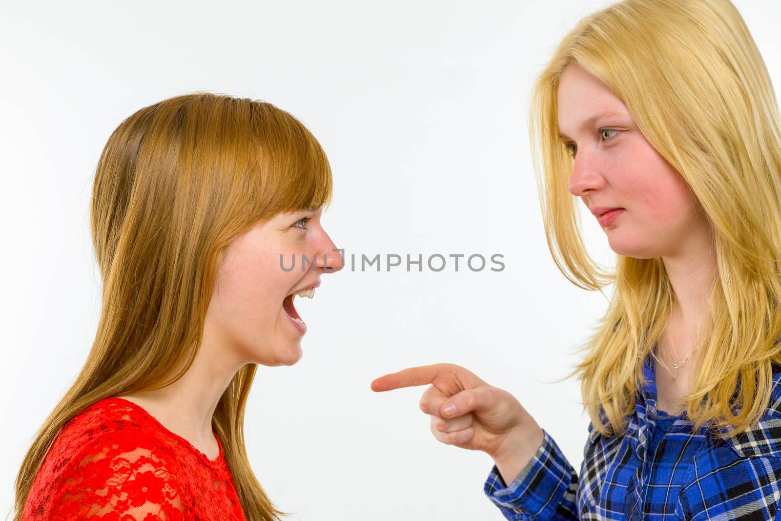 Blonde caucasian girl pointing at red haired girlfriend isolated on white background