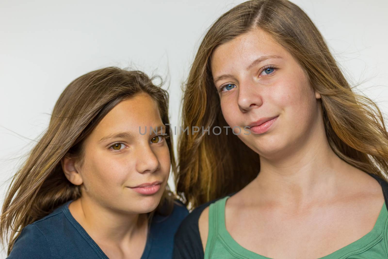 Portrait of two caucasian teenage girls with long blown hair isolated on white background