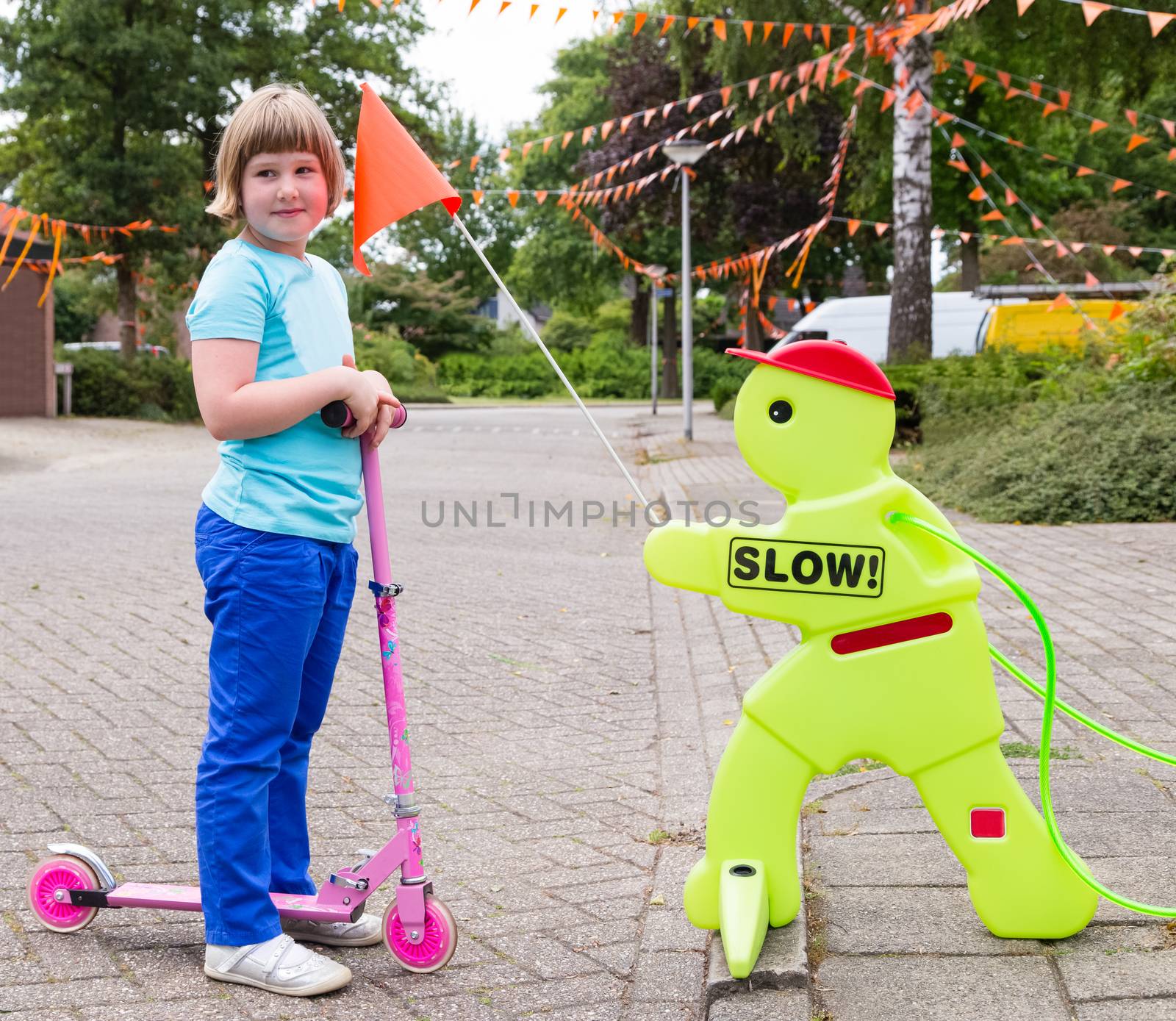 Young caucasian girl on pink  scooter with safety figurine in street