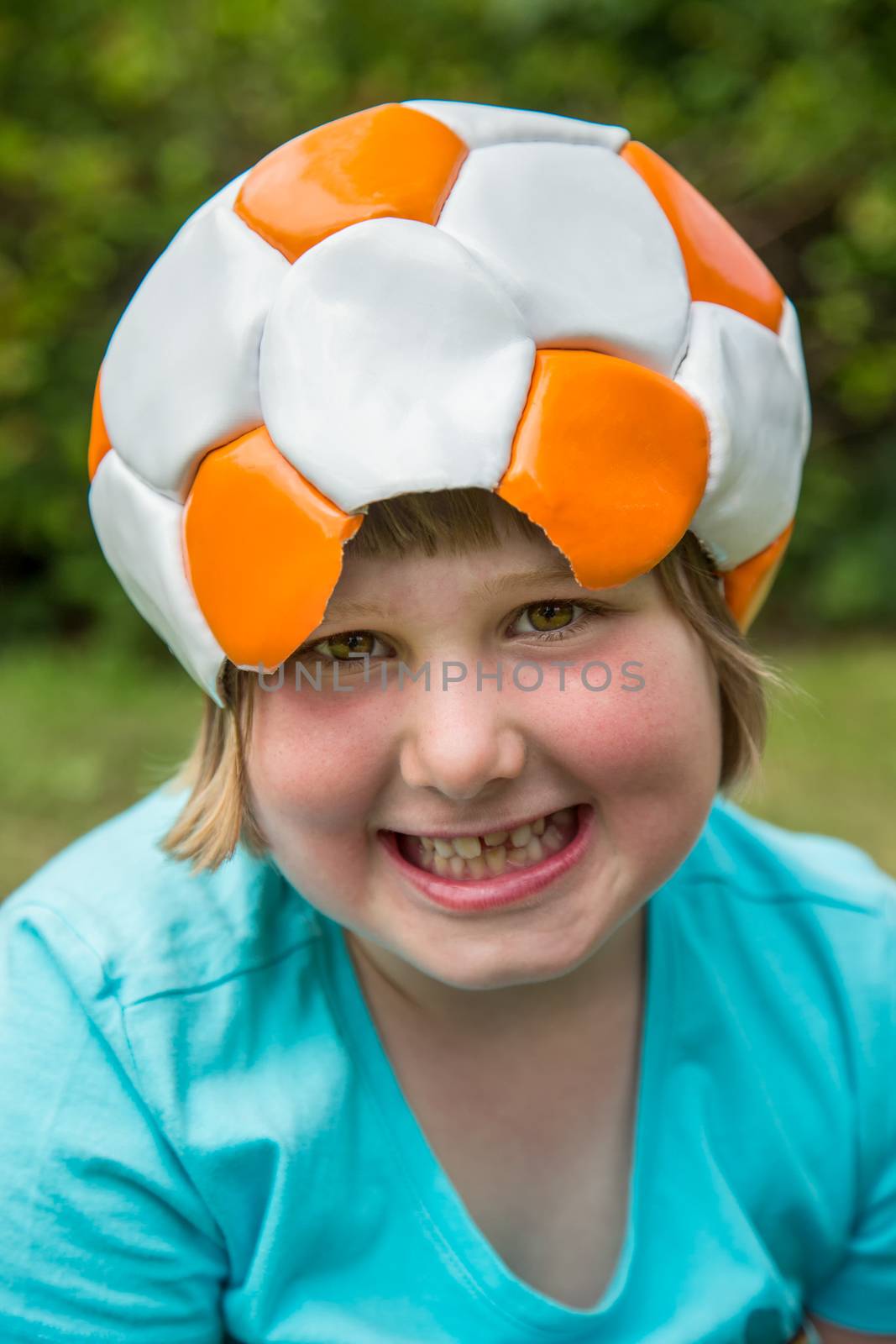 Young european girl wearing leather football on head is laughing at camera