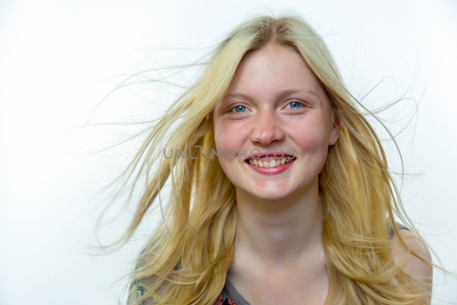 Caucasian blonde teenage girl with hair in wind isolated on white background