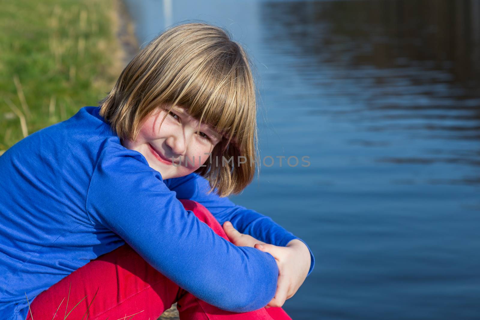 Young girl sitting at waterfront by BenSchonewille