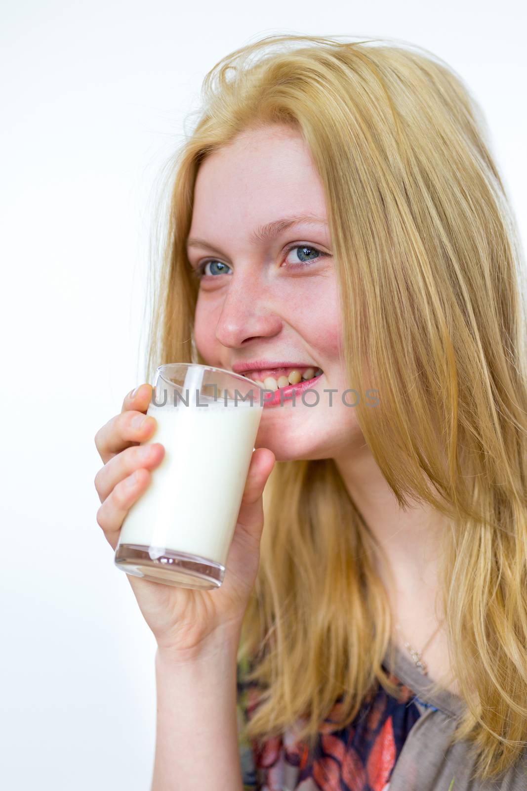 Blond caucasian teenage girl drinking glass of milk isolated on white background
