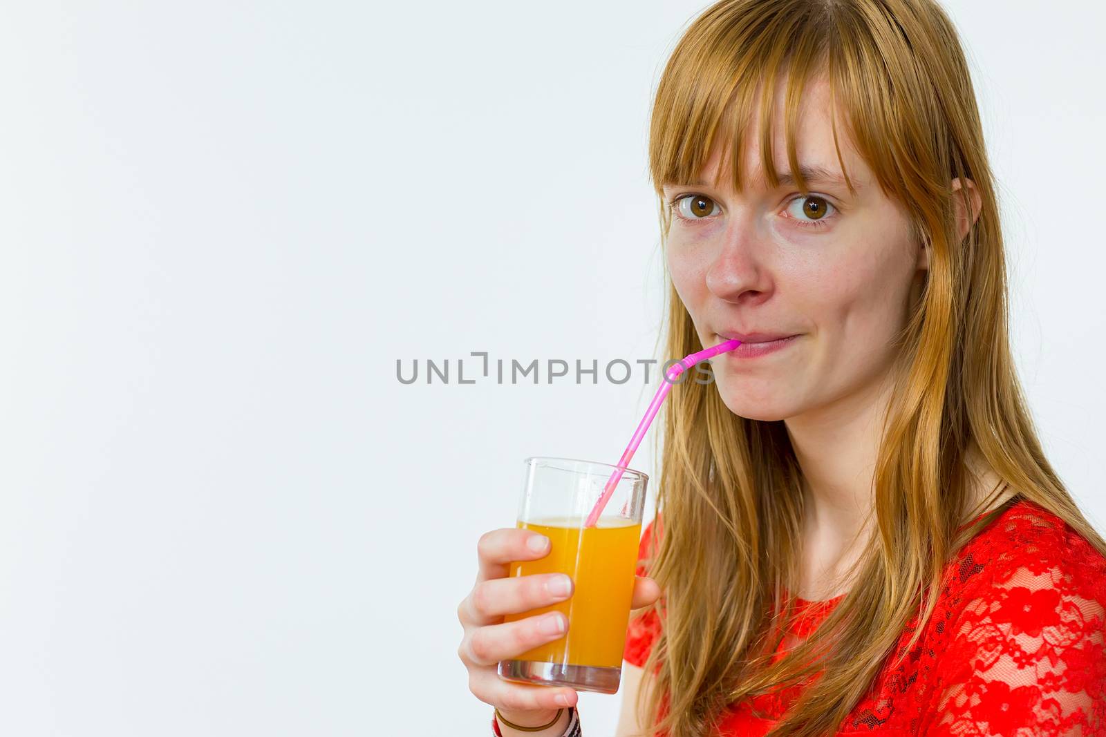Redhead caucasian teenage girl drinking orange juice with straw isolated on white background