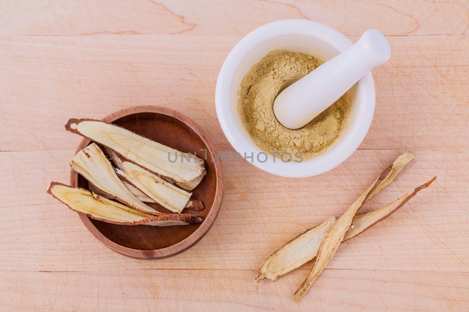 Licorice herbal medicine including powder, chopped and sliced root and mortar on wooden table