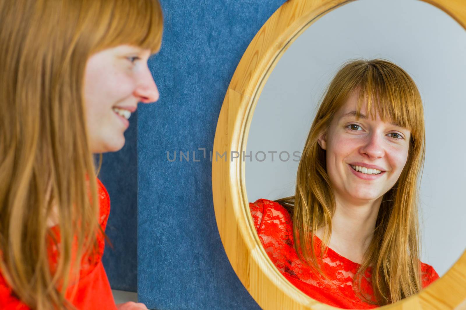 Portrait of caucasian redhead teenage girl looking in mirror
