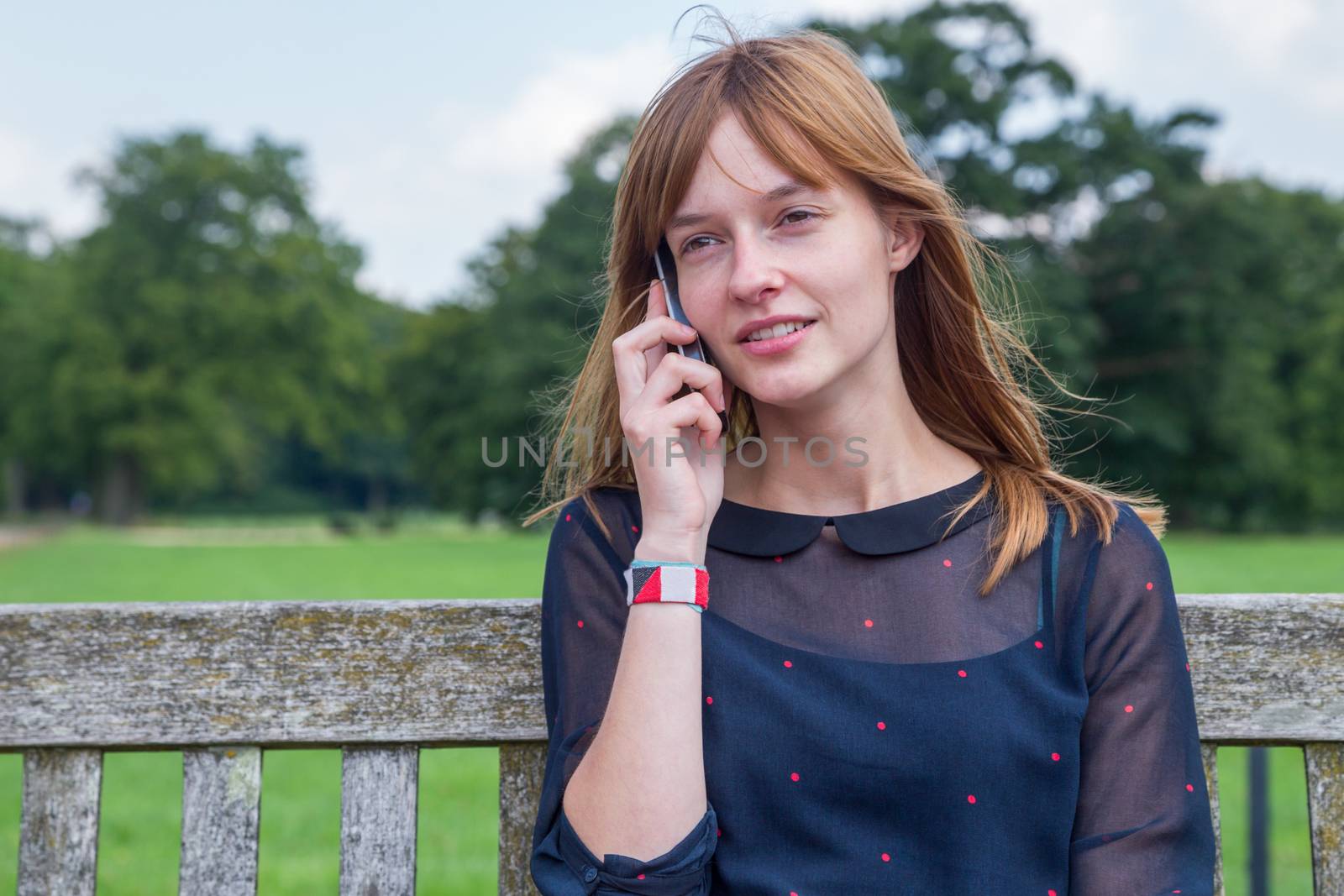 Caucasian teenage girl with red hair phoning with mobile phone in nature