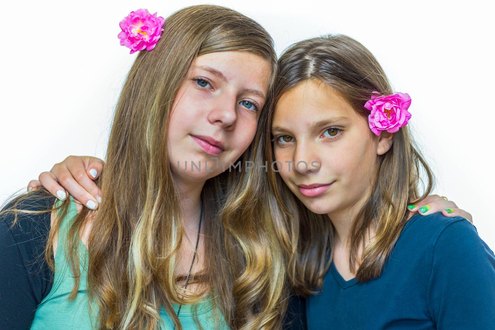 Two caucasian teenage sisters wearing pink roses embracing each other