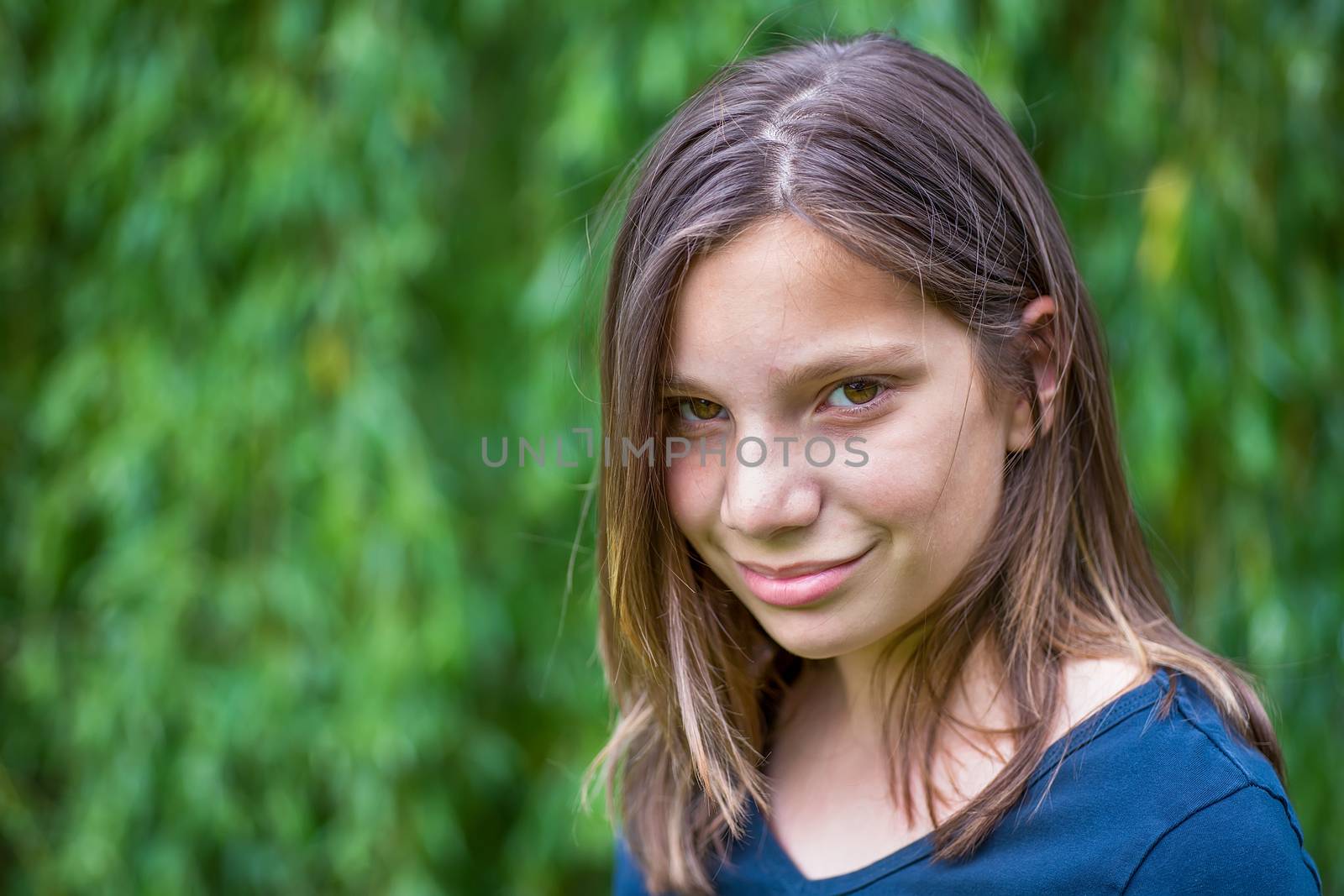 Portrait of caucasian teenage girl in front of green willow