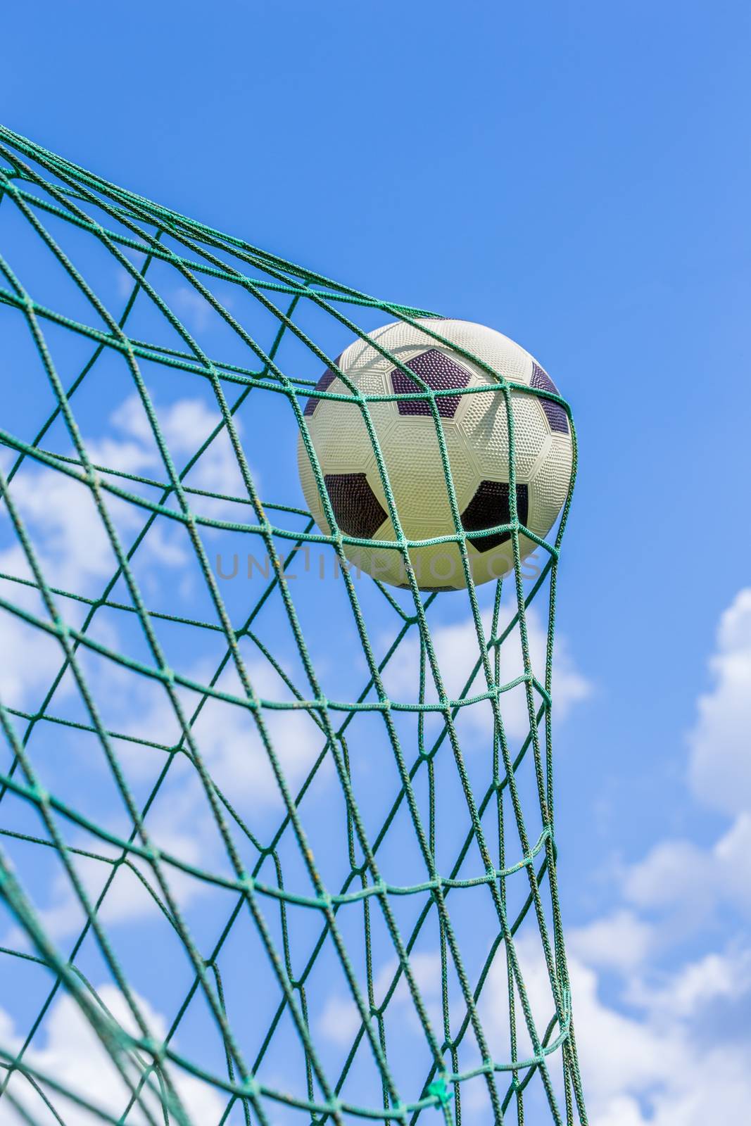 Football caught in goal net with blue sky by BenSchonewille