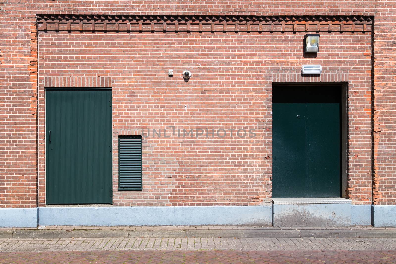 Old brick wall with green doors and street