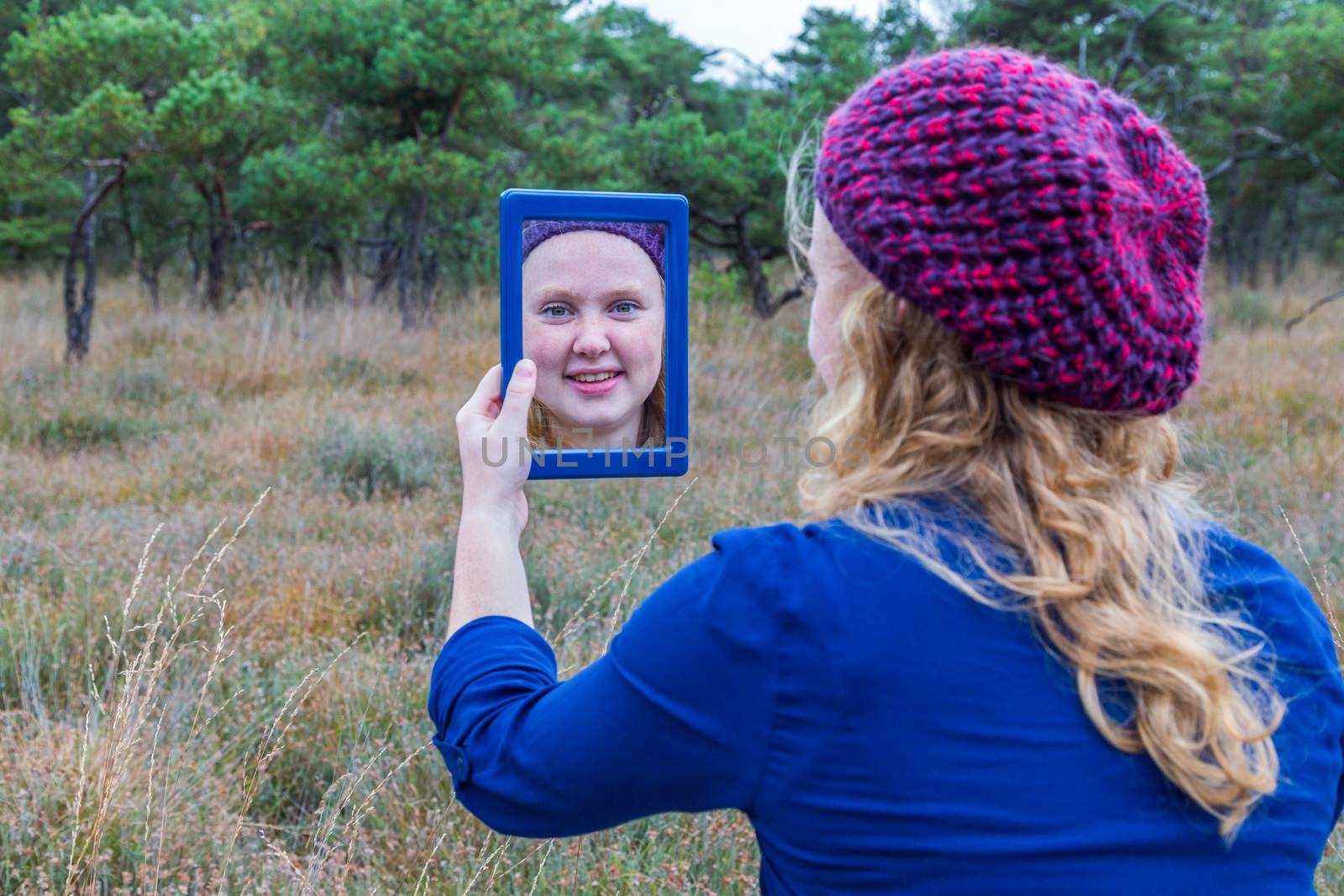 Dutch teenage girl holding mirror in nature and looking at herself