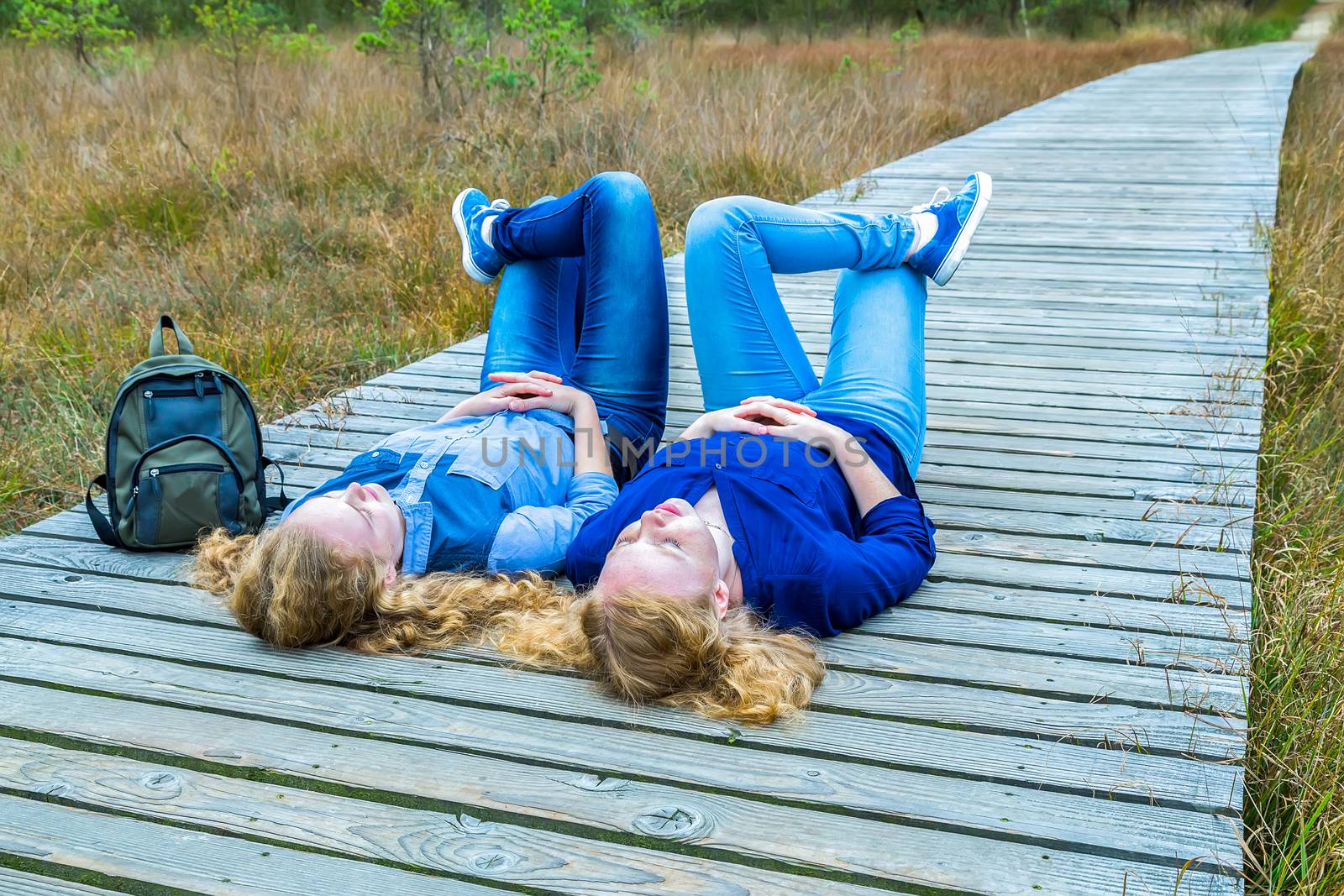 Two girls lying on their backs in nature by BenSchonewille