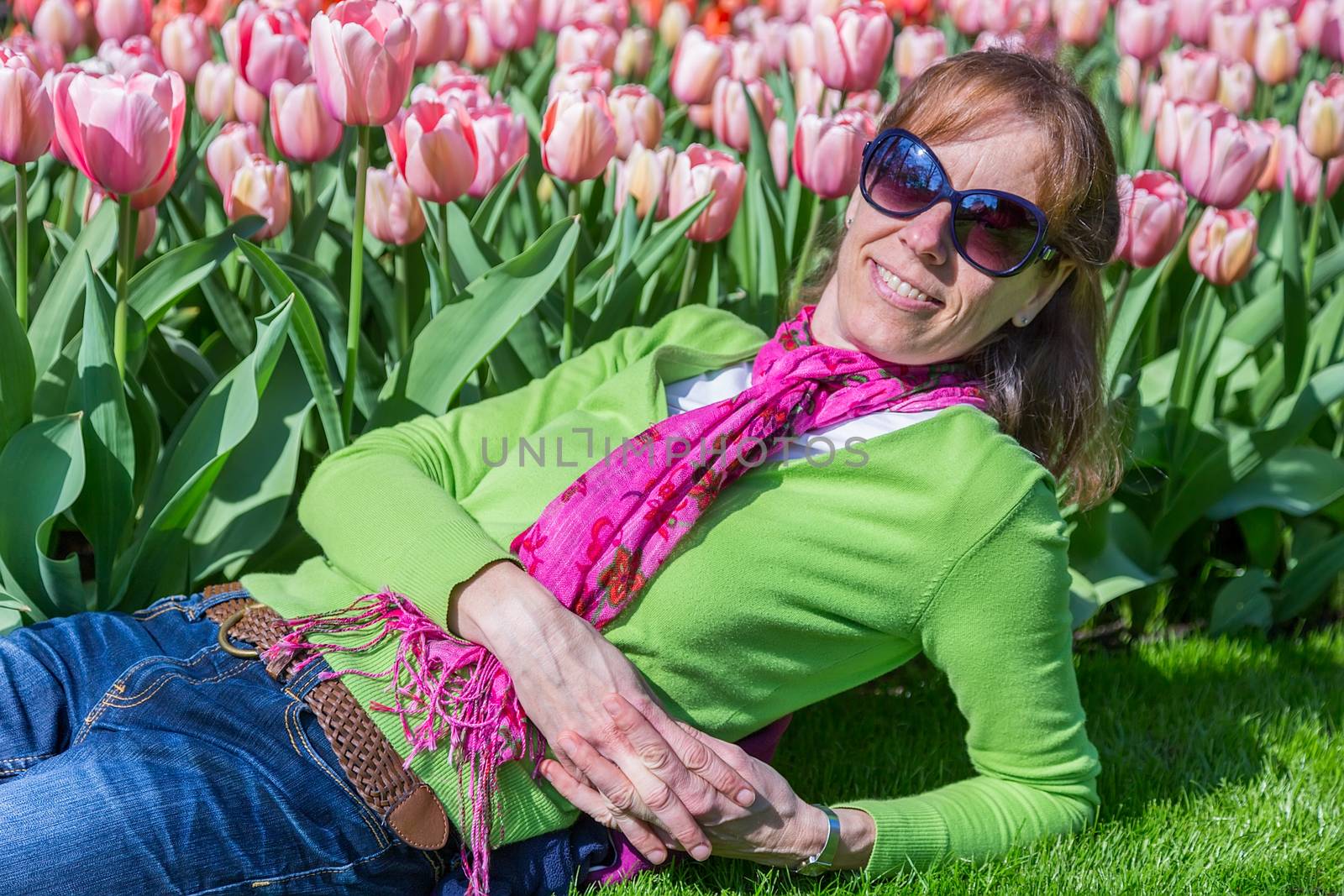 Caucasian woman lying in front of pink tulip field