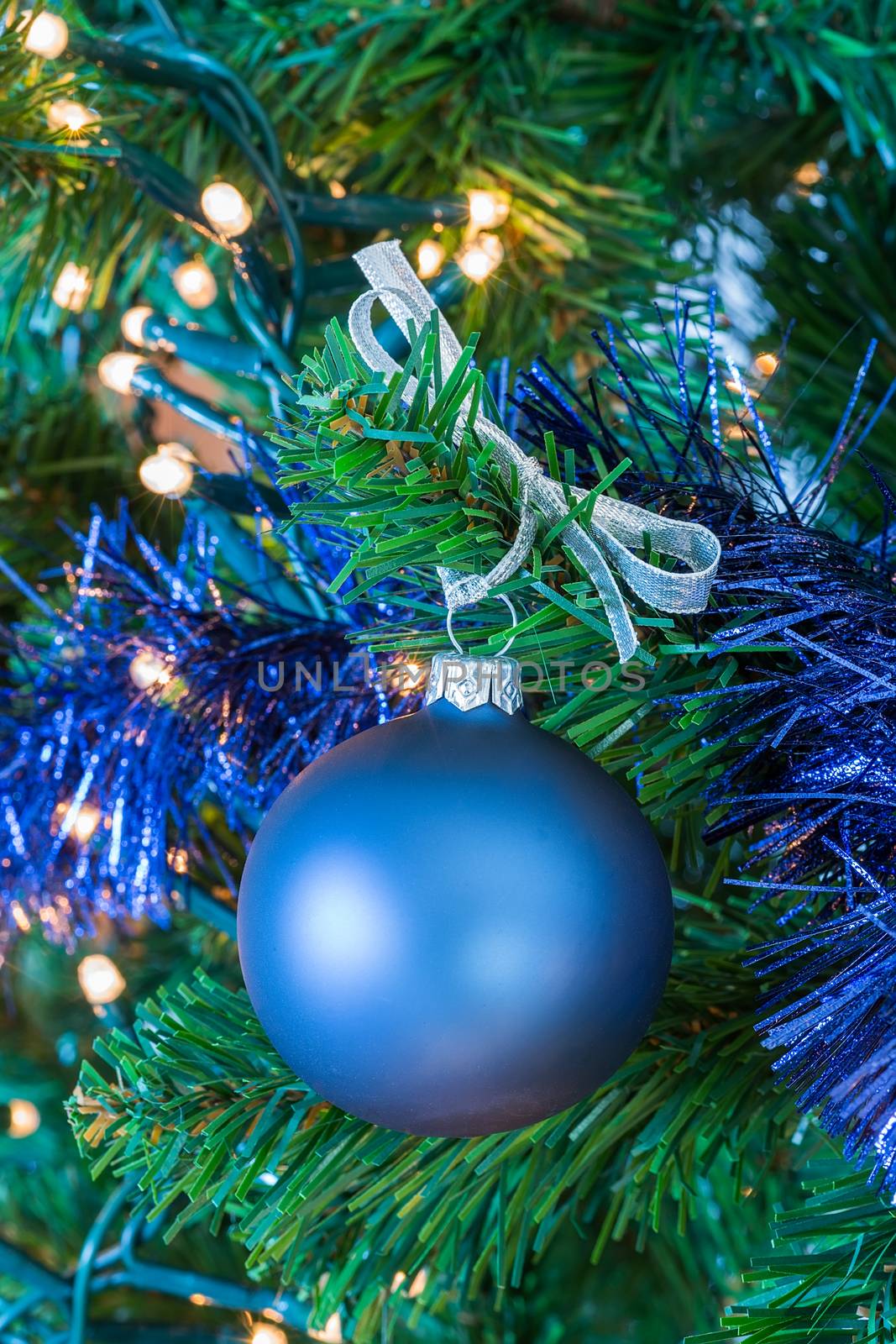 Blue Christmas ball hanging in tree by BenSchonewille