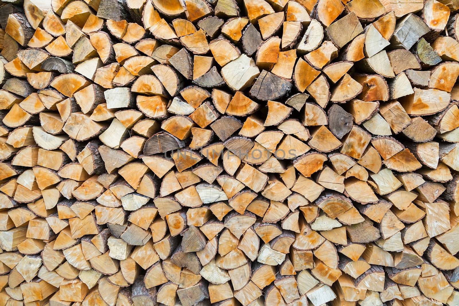 Pile of firewood as tree trunks storage for burning in winter