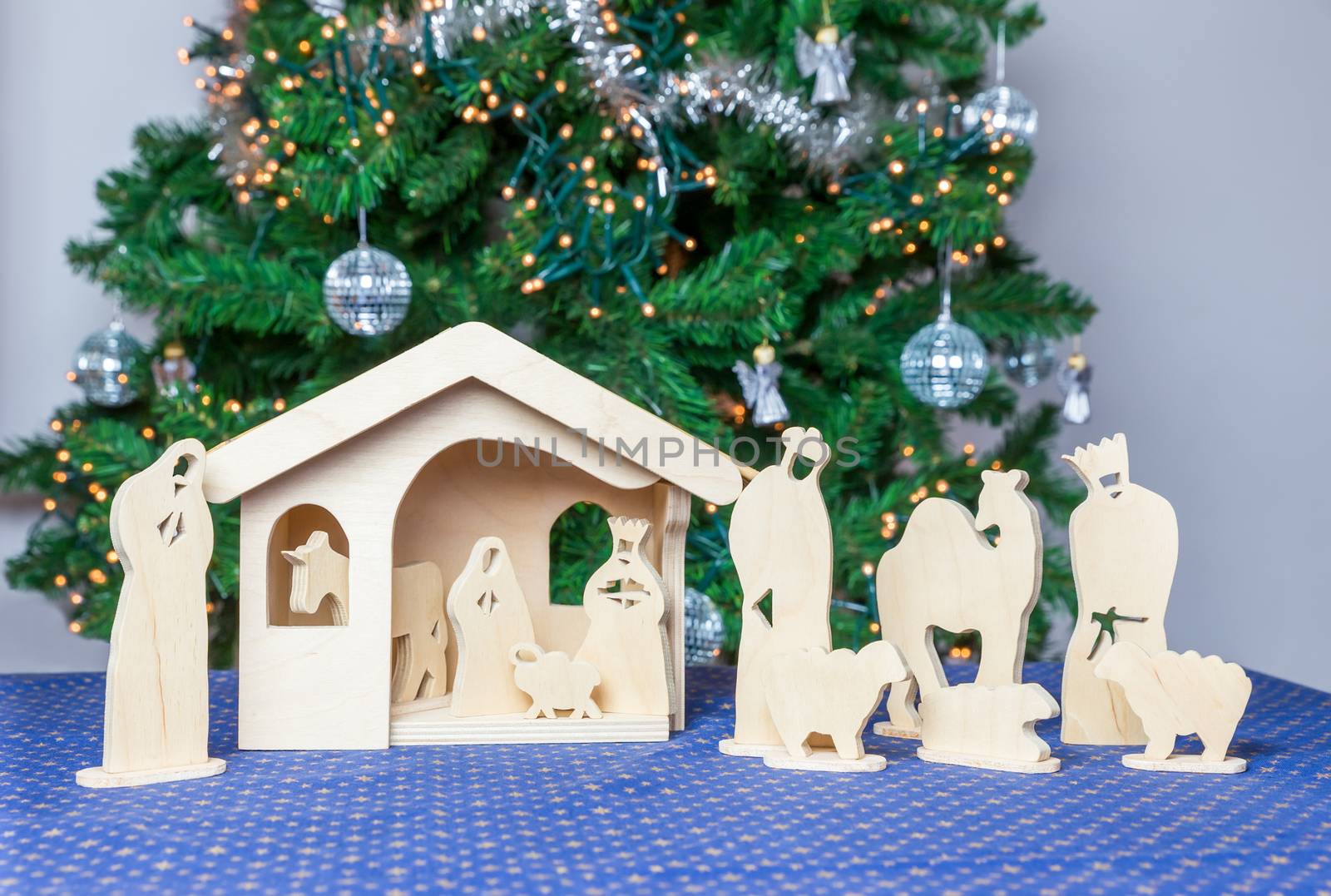 Wooden christmas stable with bible figurines and tree on background