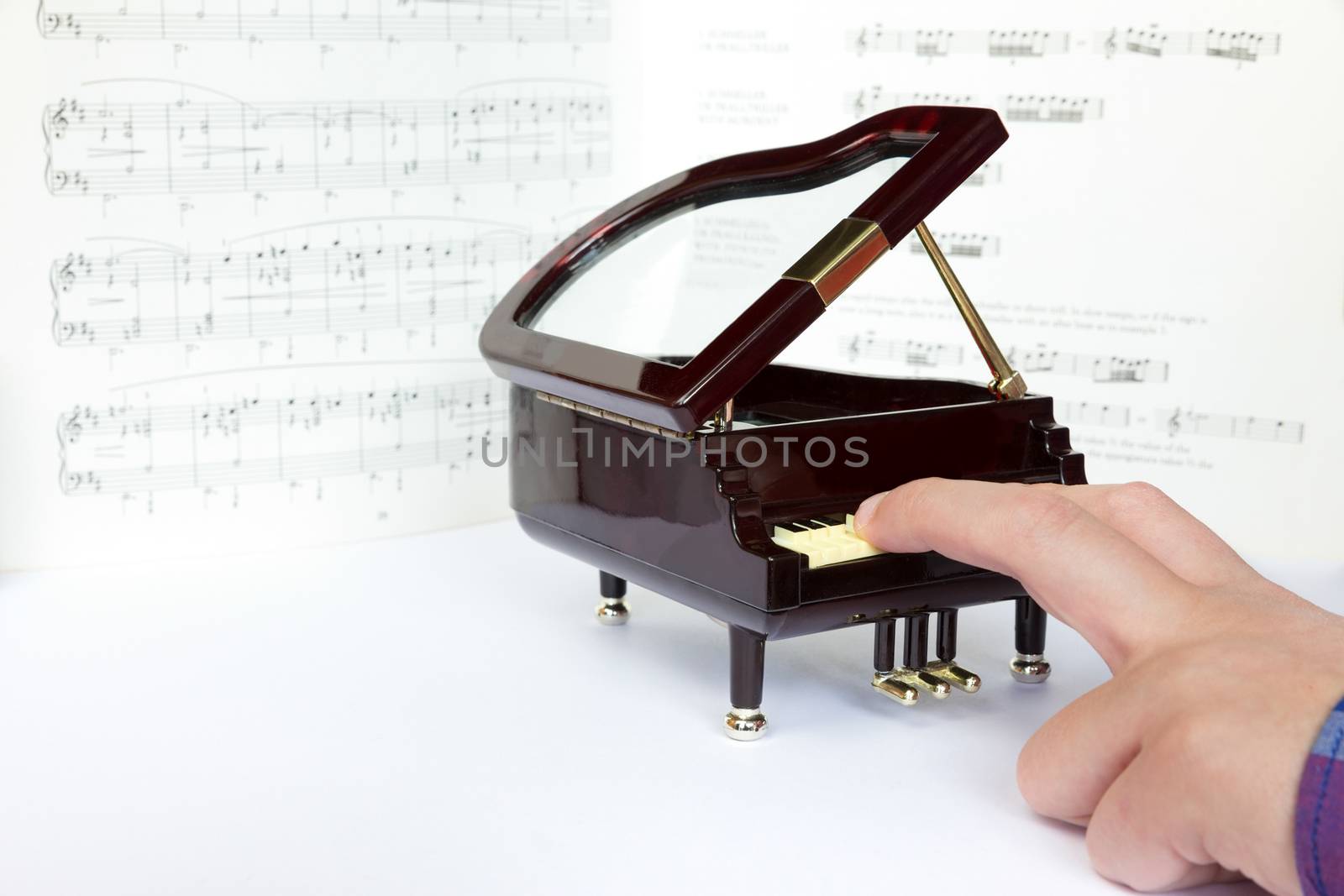 Fingers playing on small model of grand piano by BenSchonewille