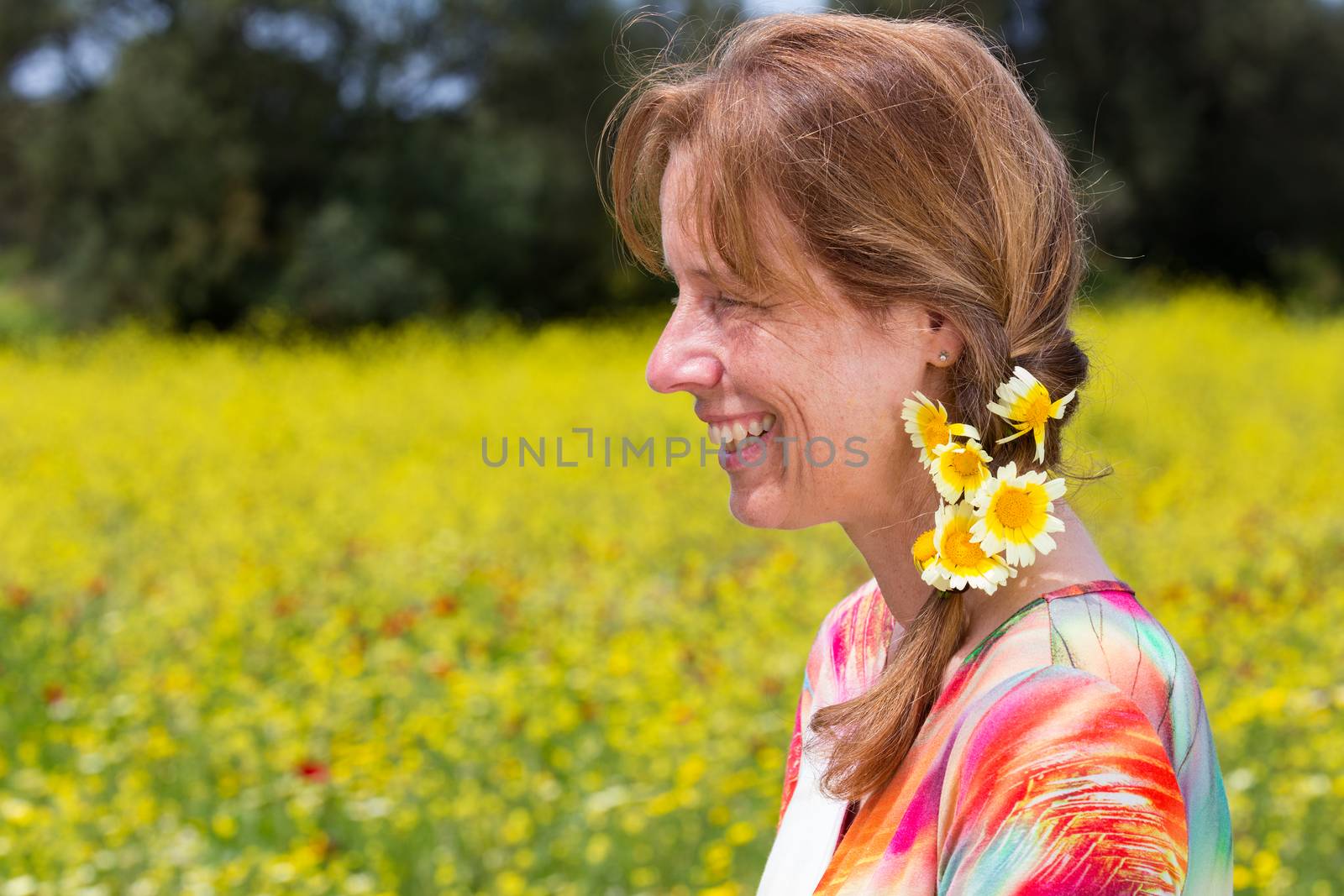 Caucasian middle aged woman wearing braid with yellow flowers near coleseed field in summer