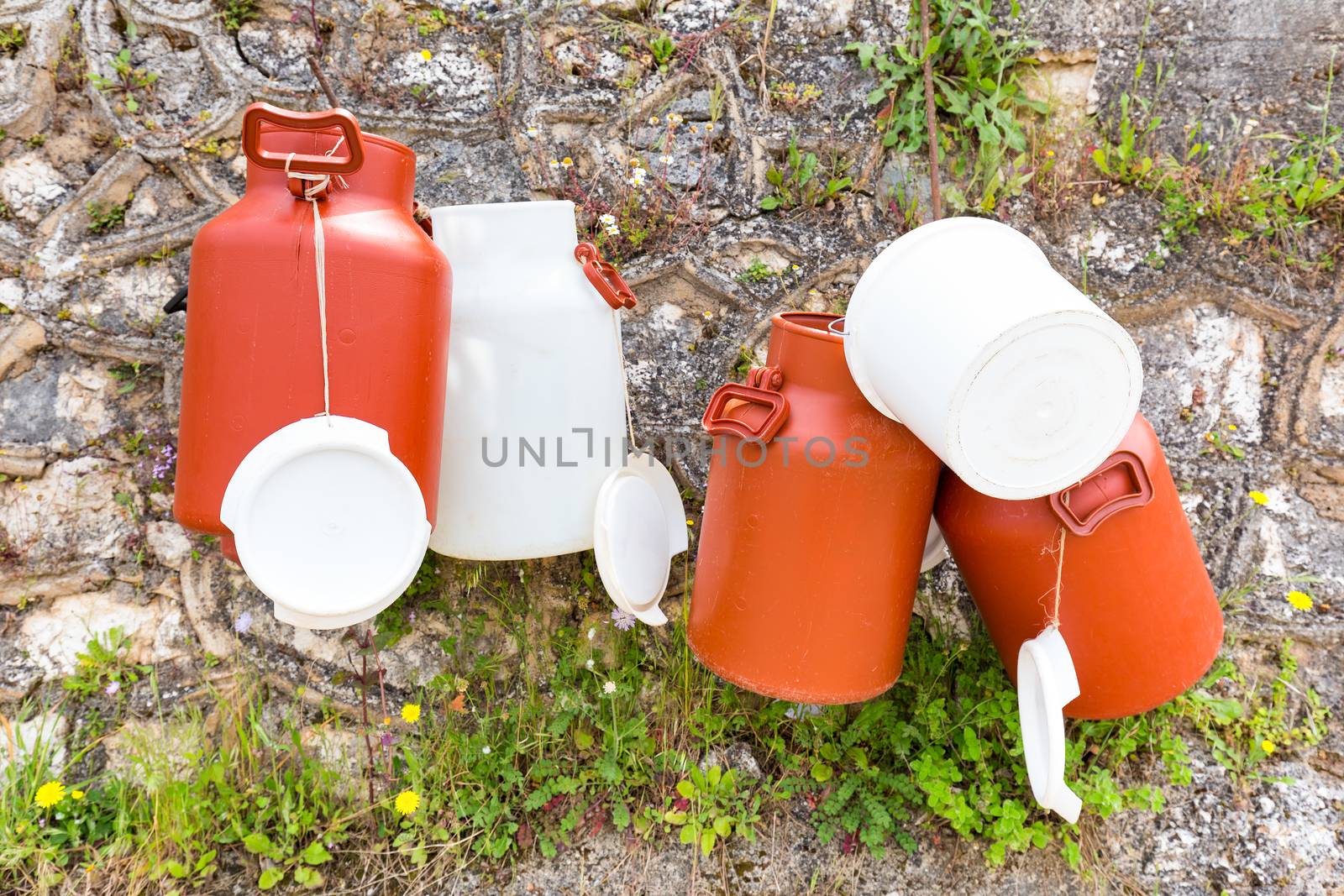 Plastic white and brown milk cans hanging at wall in Greece