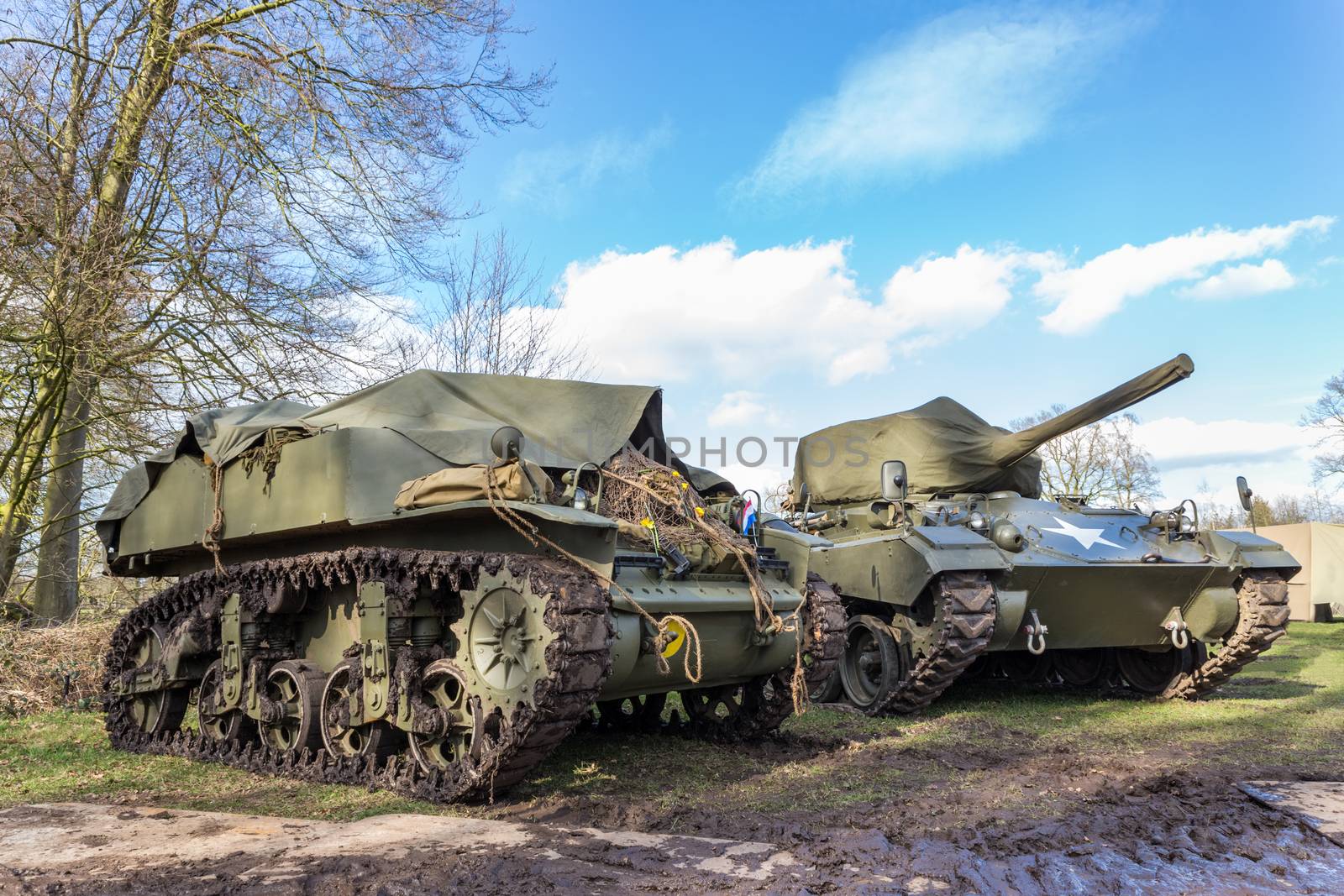 Two military tanks parked for exhibition in nature with blue sky and white clouds