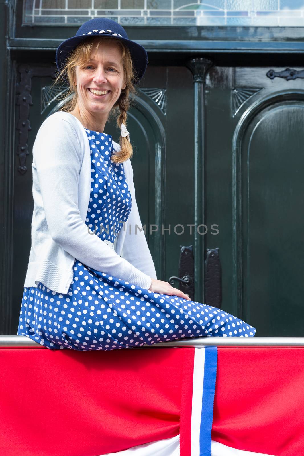 Caucasian middle aged woman in old-fashioned clothes with dutch flag to celebrate liberation day