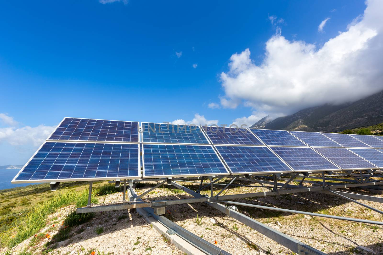 Row of solar collectors on mountain with blue sky by BenSchonewille