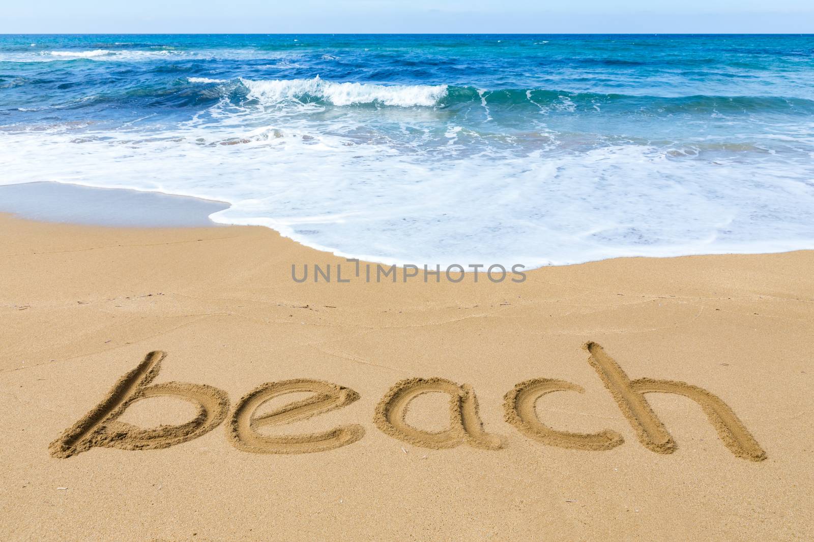 Word beach written in sandy coast with blue sea