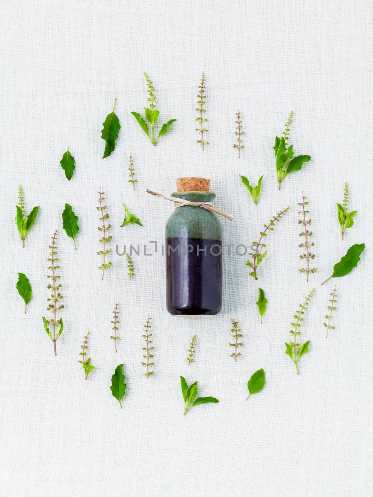 Bottle of essential oil, with holy basil leaf and flower.